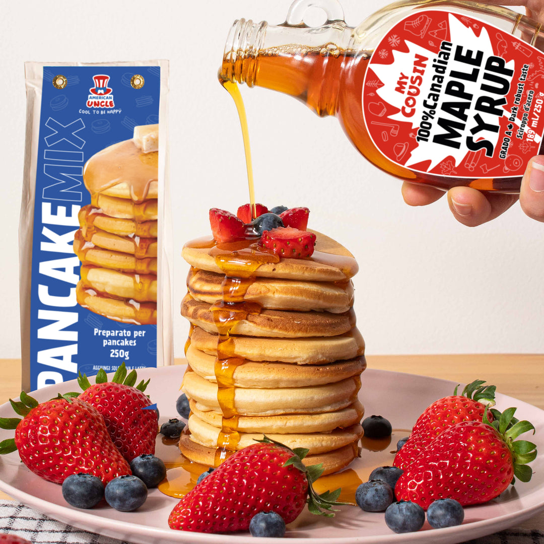 Pila di pancake con fragole, mirtilli e sciroppo d'acero che viene versato dalla confezione da 189ml di My Cousin